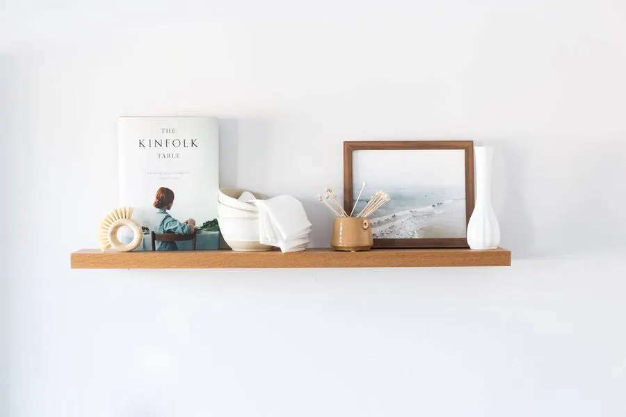 A thin white oak floating shelf styled with books and decor, photo from ultrashelf.com.